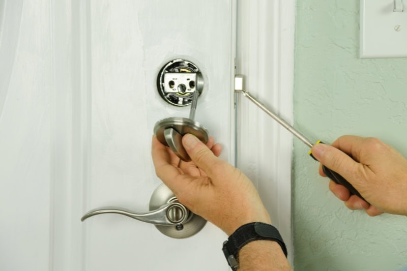 The Difference Between a Left-Hand and Right-Hand Door. Close up photo of a locksmith professional repairing or installing a deadbolt on a door.